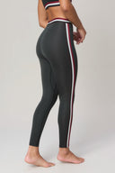 Charcoal high-waisted leggings with red and white side stripes, modeled from the side.
