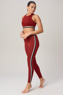 Woman modeling high-waisted merlot red leggings with side stripe and matching sports bra.